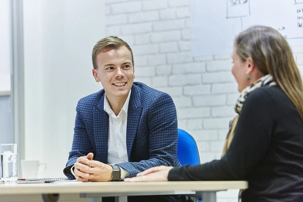 Two team members smiling in an office