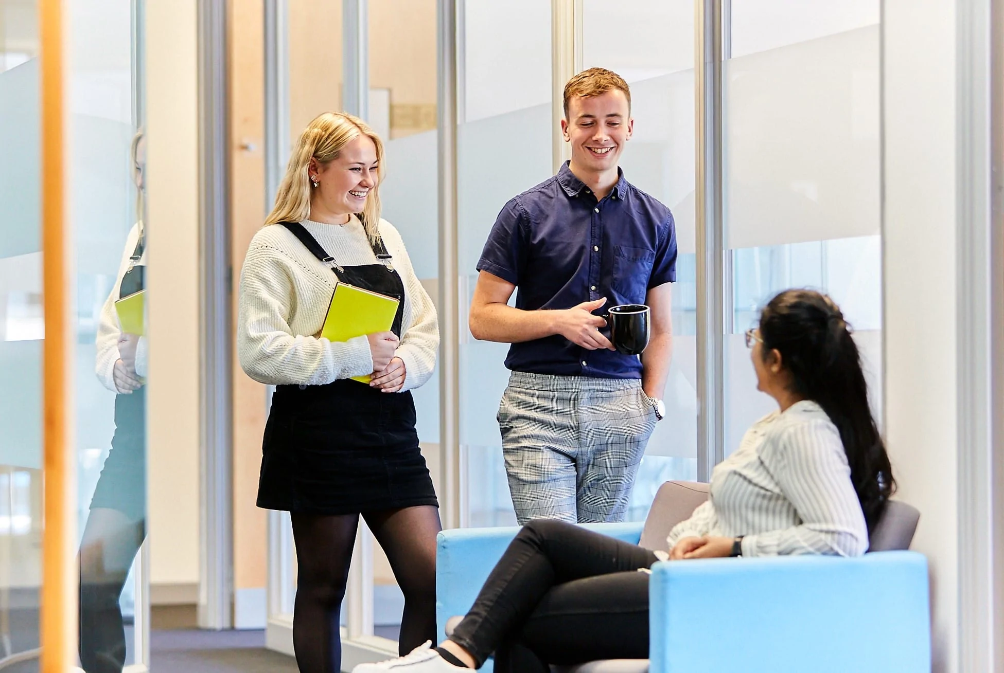 Three team members smiling and chatting in an office